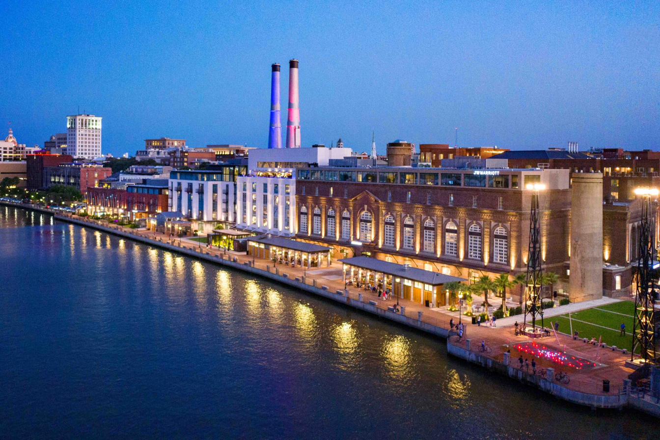 Savannah riverfront at dusk, the historic Plant Riverside power-station district lit along the Savannah River